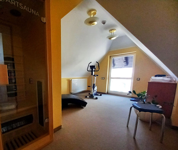 Ein Blick in unseren Wellness-Bereich mit Hometrainer, Sauna und Massageliege.
